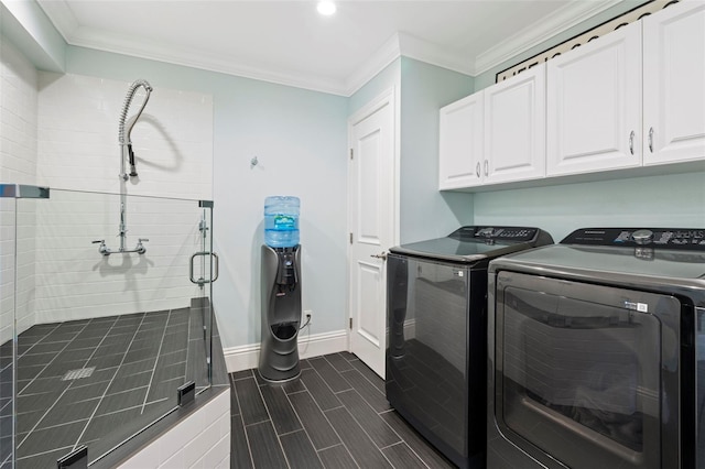 washroom featuring ornamental molding, washing machine and dryer, and cabinets