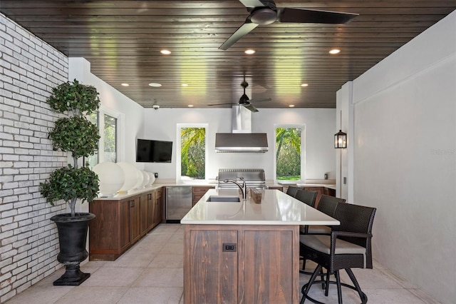 exterior space featuring wood ceiling, wall chimney exhaust hood, brick wall, and a center island with sink