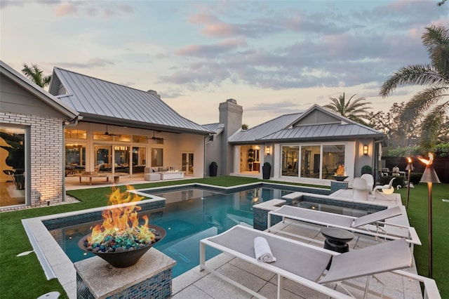 pool at dusk with a fire pit and a patio area