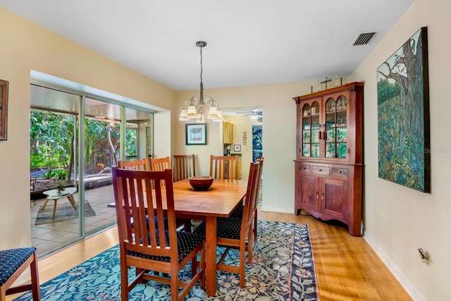 dining space with light hardwood / wood-style floors and a notable chandelier