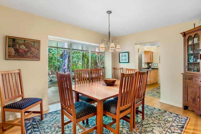 dining room featuring sink, an inviting chandelier, and light hardwood / wood-style flooring