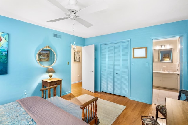 bedroom featuring ceiling fan, ensuite bath, light wood-type flooring, and a closet