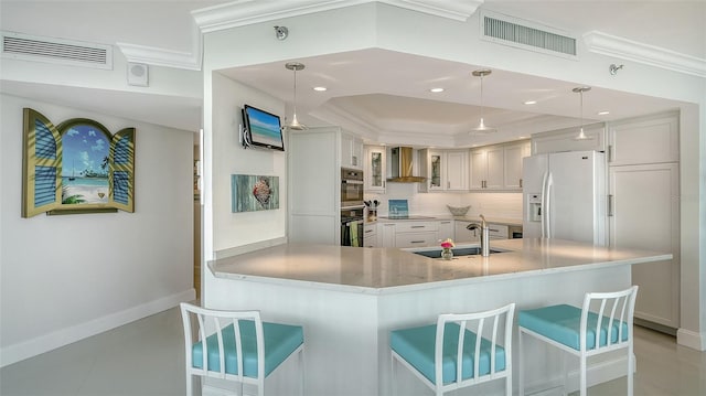 kitchen featuring black appliances, wall chimney exhaust hood, visible vents, and a sink