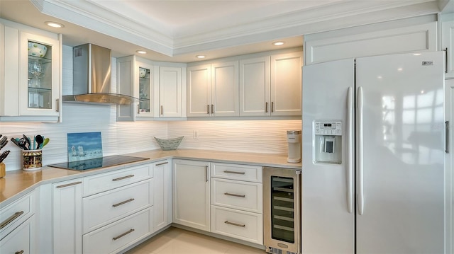 kitchen featuring light countertops, wall chimney range hood, white fridge with ice dispenser, beverage cooler, and black electric cooktop