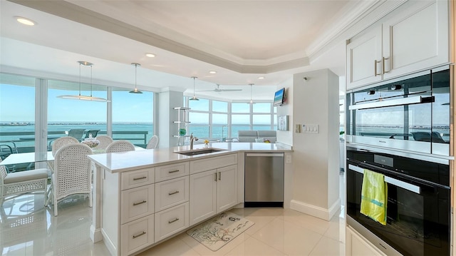 kitchen with a tray ceiling, decorative light fixtures, light tile patterned floors, a sink, and dishwasher