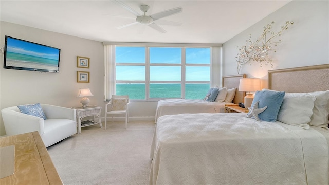 bedroom featuring baseboards, carpet, a ceiling fan, and a water view