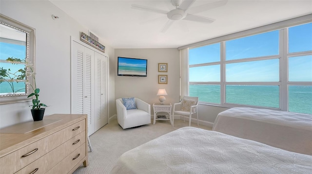 bedroom with baseboards, a ceiling fan, a closet, and light colored carpet