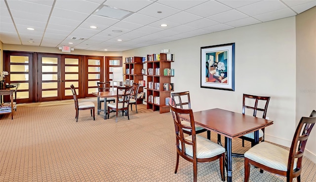 dining space with a paneled ceiling, recessed lighting, light colored carpet, baseboards, and french doors