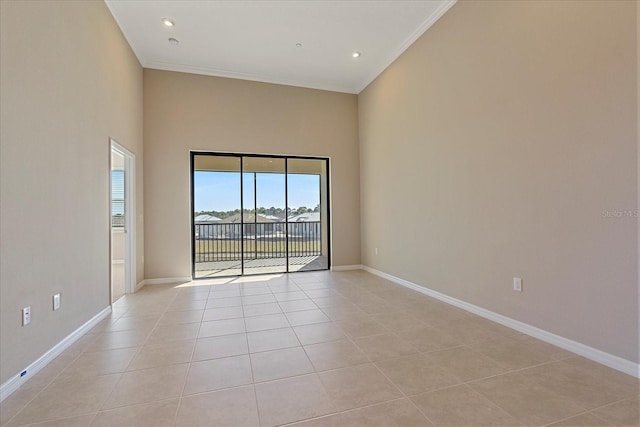 spare room with light tile patterned floors, crown molding, and a towering ceiling