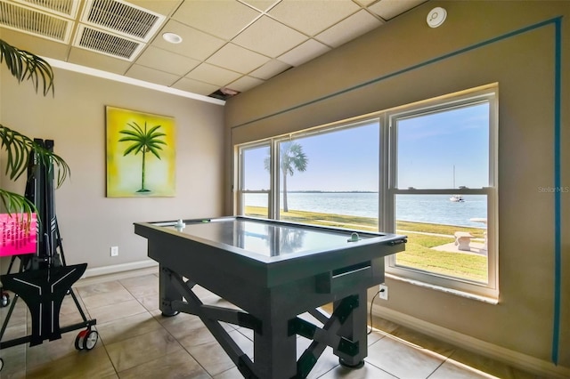 game room with light tile patterned floors, plenty of natural light, a paneled ceiling, and a water view