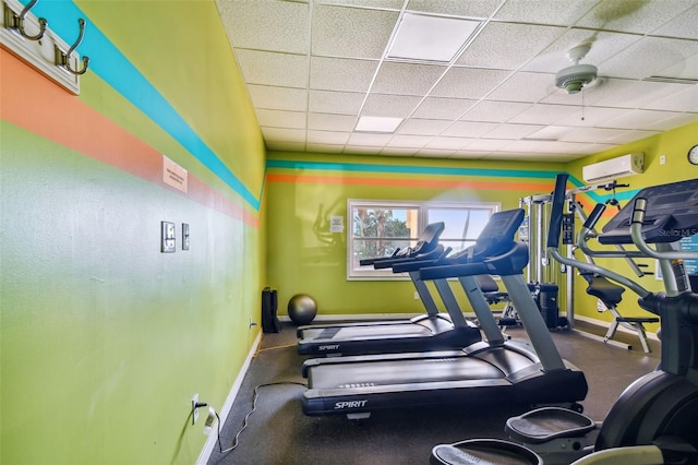 exercise area featuring a paneled ceiling and an AC wall unit