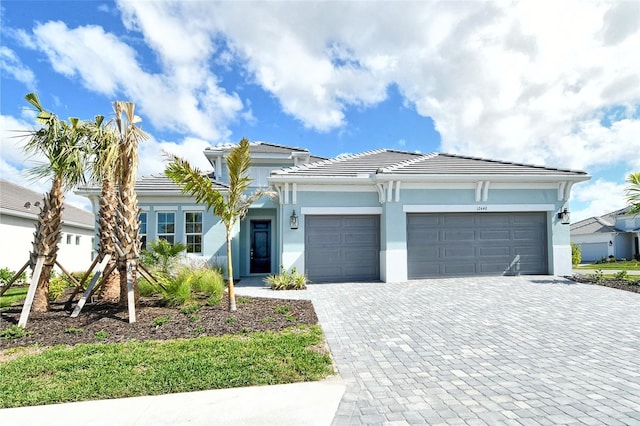 12440 Meribel St, Venice, FL 34293 - view of front facade with a tiled roof, decorative driveway, a garage, and stucco siding