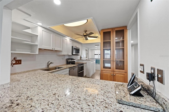 kitchen featuring sink, light stone countertops, white cabinets, and appliances with stainless steel finishes