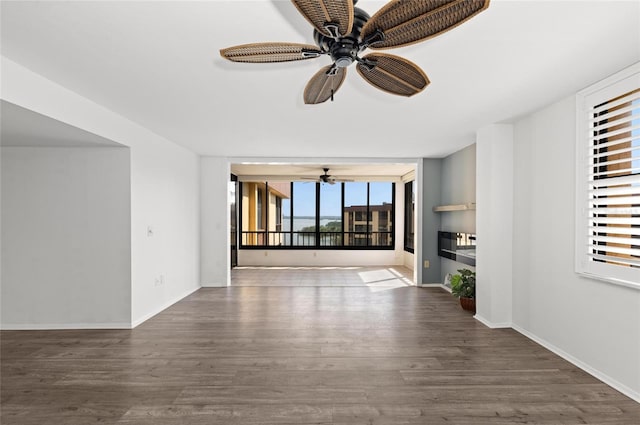 unfurnished living room featuring dark wood-type flooring, ceiling fan, and a wall of windows