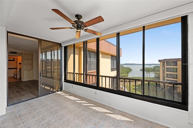 unfurnished sunroom with a water view and ceiling fan