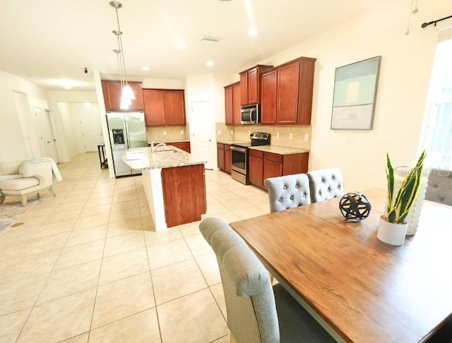5718 Broad River Run, Ellenton, FL 34222 - kitchen featuring stainless steel appliances, decorative backsplash, light tile patterned floors, a kitchen island with sink, and light stone countertops