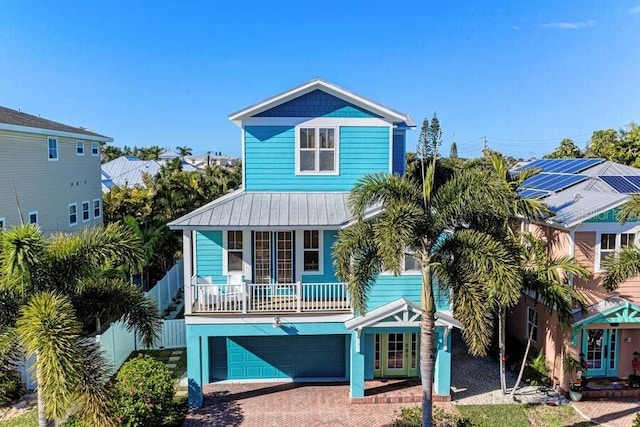 beach home featuring a garage, metal roof, decorative driveway, and fence