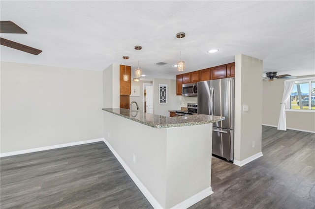 kitchen with sink, appliances with stainless steel finishes, dark hardwood / wood-style floors, decorative light fixtures, and kitchen peninsula