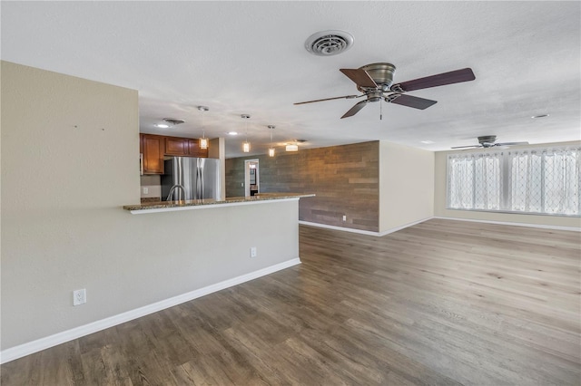 unfurnished living room with ceiling fan, dark wood-type flooring, and a textured ceiling