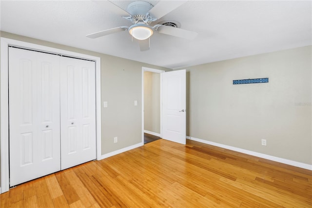 unfurnished bedroom with wood-type flooring, ceiling fan, and a closet