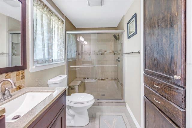 bathroom with a shower with door, vanity, tasteful backsplash, tile patterned floors, and toilet