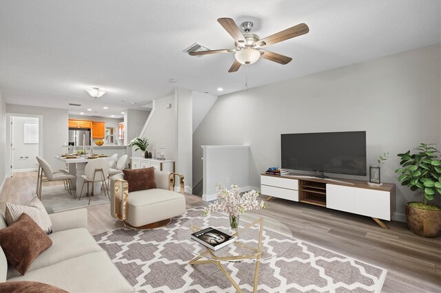 living room featuring light hardwood / wood-style flooring and ceiling fan