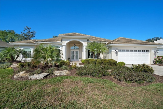 view of front of home with a garage, a front lawn, and french doors