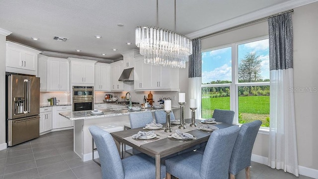 tiled dining area featuring crown molding, a healthy amount of sunlight, sink, and an inviting chandelier