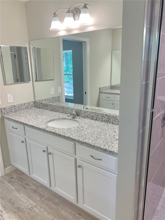 bathroom featuring hardwood / wood-style flooring, vanity, a textured ceiling, and walk in shower