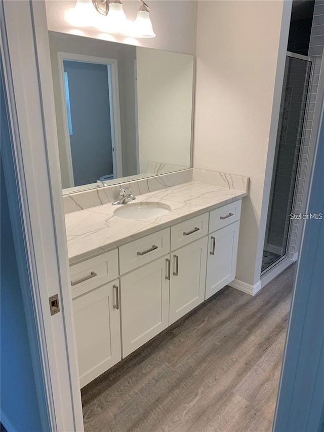 bathroom featuring wood-type flooring, an enclosed shower, and vanity