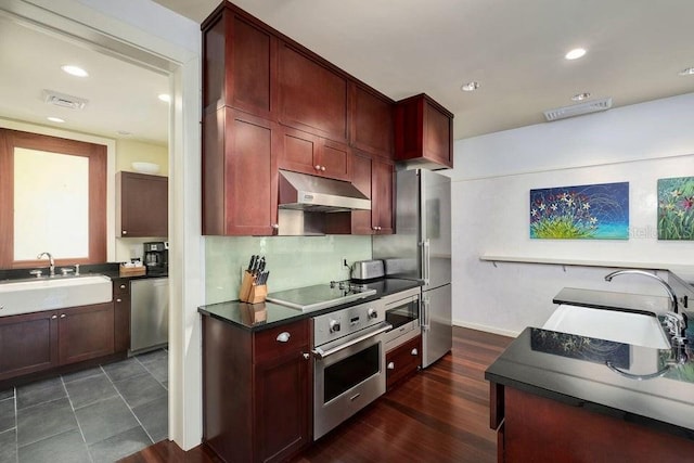 kitchen featuring stainless steel appliances, tasteful backsplash, sink, and dark wood-type flooring