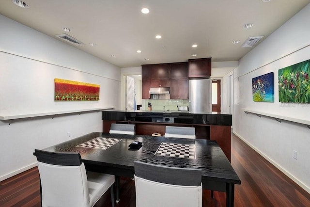 kitchen with dark wood-type flooring, dark brown cabinets, and backsplash