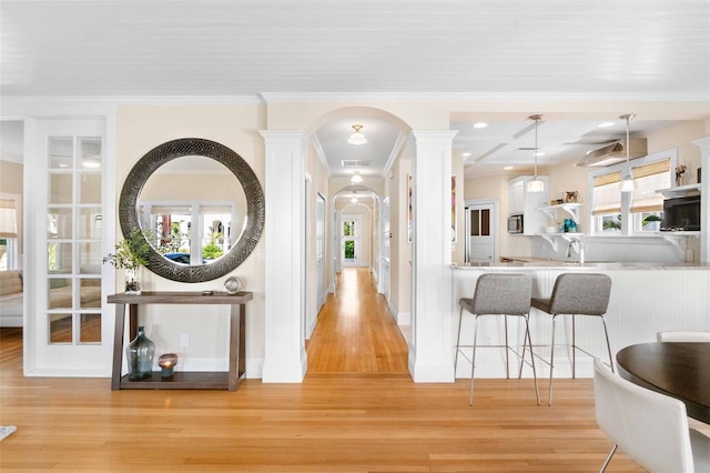 hall featuring decorative columns, crown molding, and light hardwood / wood-style flooring