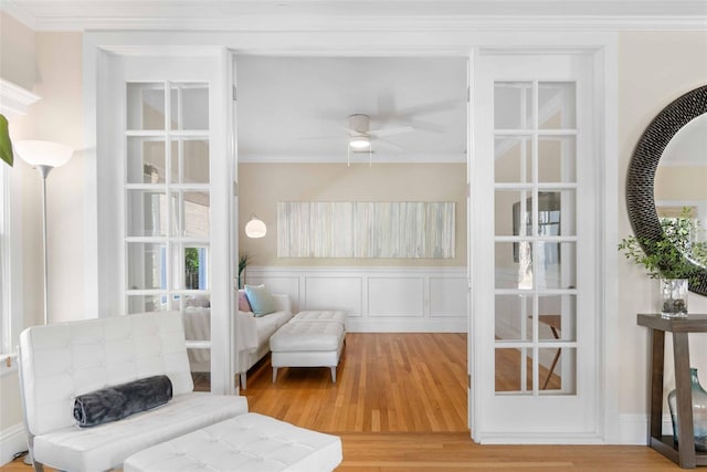 living area with hardwood / wood-style floors, ornamental molding, and ceiling fan