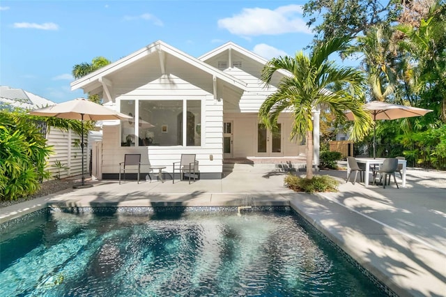 rear view of house featuring a fenced in pool and a patio