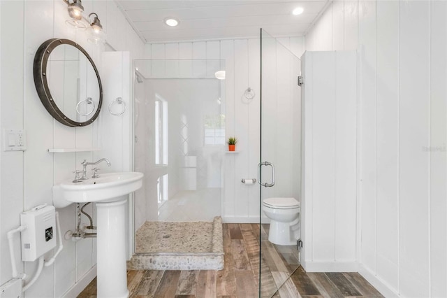 bathroom with wood-type flooring, a shower with shower door, and toilet