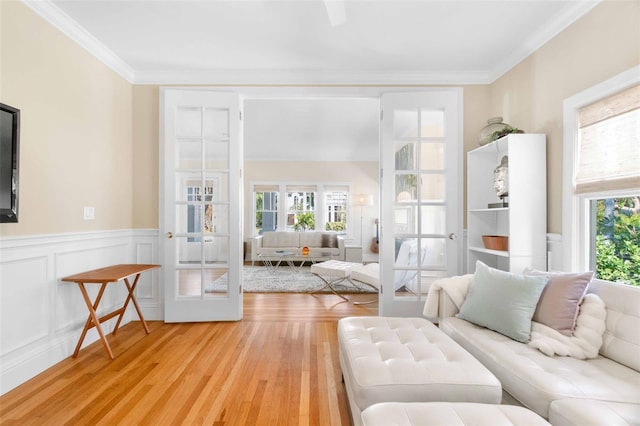 living room with french doors, ornamental molding, light wood-type flooring, and a wealth of natural light