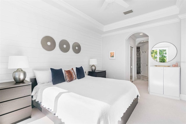 bedroom featuring light colored carpet, ornamental molding, and a tray ceiling