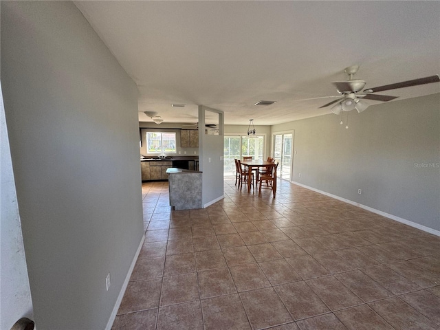 interior space featuring ceiling fan, dark tile patterned floors, visible vents, and baseboards