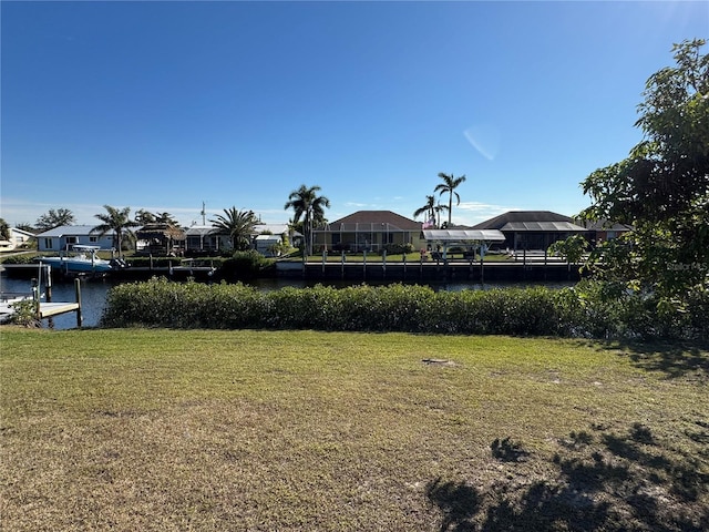 view of yard with a residential view, a water view, and a boat dock