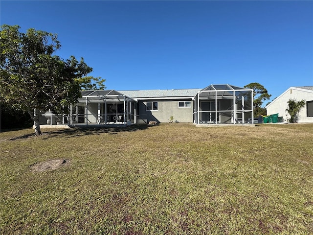 rear view of house featuring a lanai, a lawn, and stucco siding