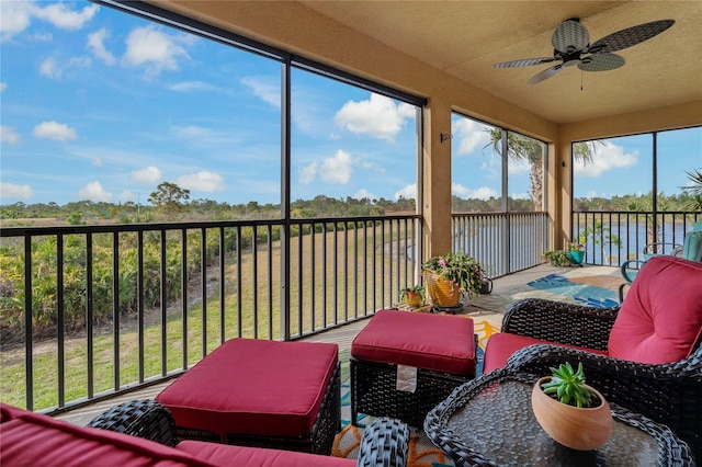 sunroom featuring a water view and ceiling fan