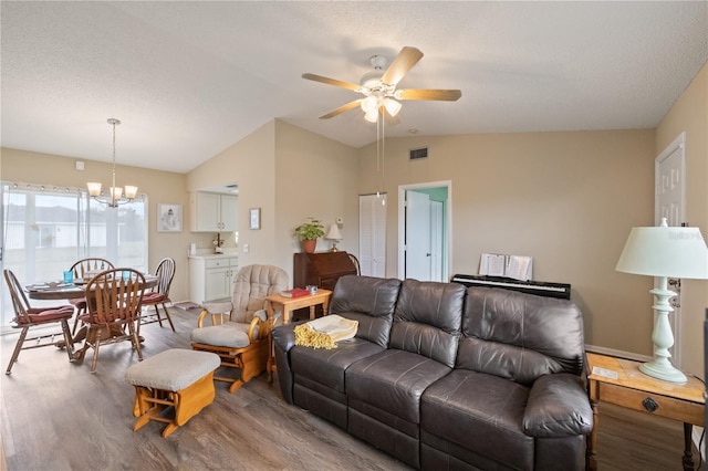 living room with wood-type flooring, lofted ceiling, ceiling fan with notable chandelier, and a textured ceiling