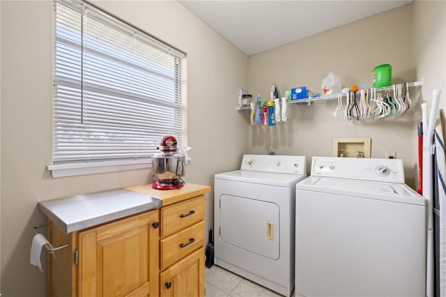 washroom featuring cabinets, washing machine and dryer, light tile patterned floors, and a textured ceiling