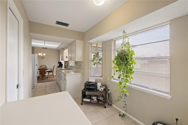 kitchen with white cabinetry, white refrigerator, sink, and light tile patterned floors