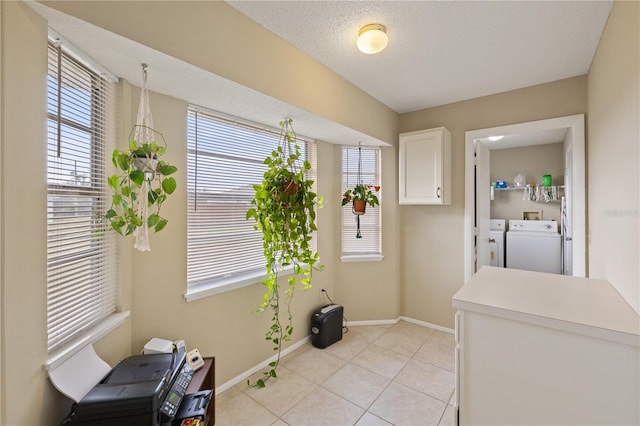 doorway featuring a textured ceiling, washer and clothes dryer, a healthy amount of sunlight, and light tile patterned flooring