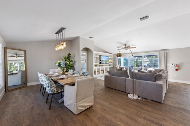 dining room featuring ceiling fan with notable chandelier, a healthy amount of sunlight, dark hardwood / wood-style flooring, and vaulted ceiling