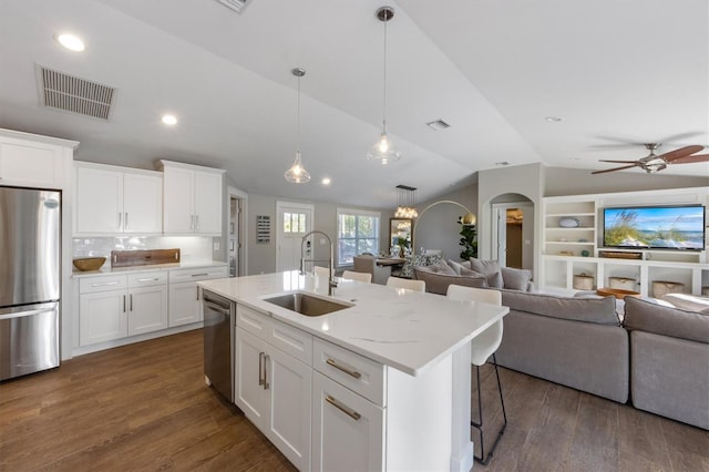 kitchen featuring appliances with stainless steel finishes, an island with sink, sink, white cabinets, and light stone countertops