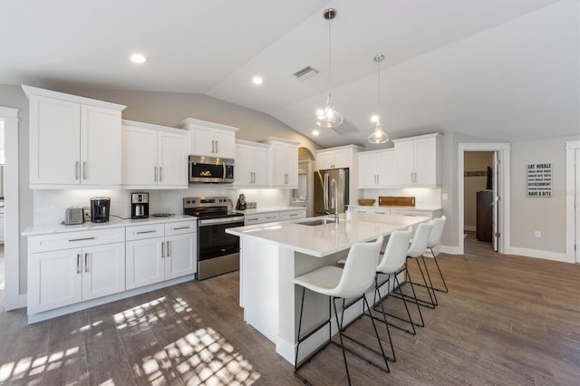 kitchen featuring a breakfast bar area, white cabinetry, appliances with stainless steel finishes, an island with sink, and pendant lighting