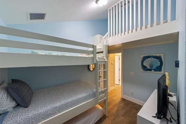 bedroom with dark wood-type flooring and high vaulted ceiling